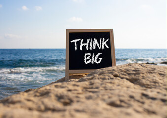 Think big symbol. Concept words Think Big on black chalk background. Beautiful sea background....