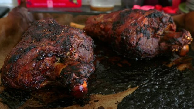 Two roasted mutton lamb leg covered with baking paper on baking tray.