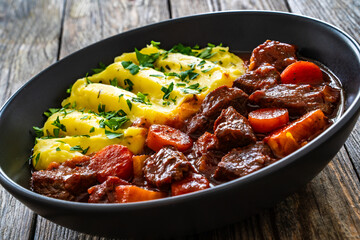 Irish stew for St. Patrick's Day - roast beef in beer with potato puree  served on wooden table
