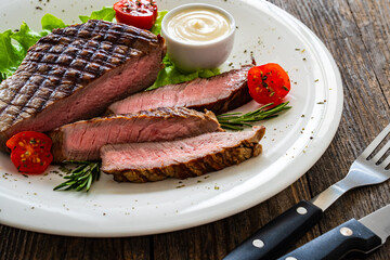 Grilled beef sirloin steak with fresh vegetables on wooden table
