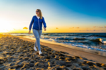 Beautiful mid adult woman walking on beach at sunset
