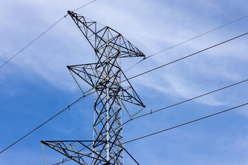 The top section of a high voltage hydro electricity distribution tower on a blue sky