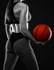 A beautiful slender girl athlete in leggings and a top plays basketball.