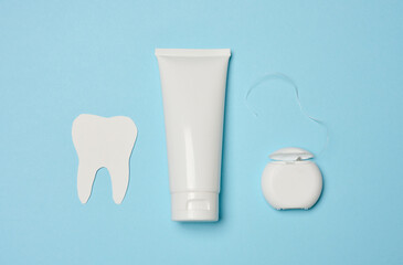 Tube with toothpaste and dental floss on a blue background