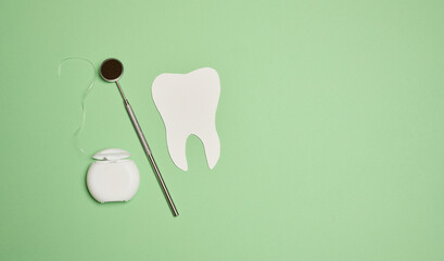 Dental floss and paper teeth on green background, oral hygiene