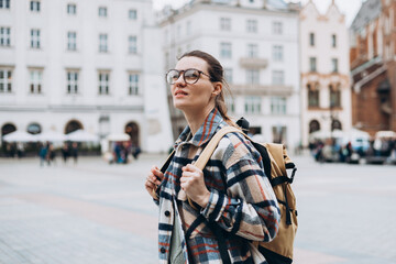 Tourist happy woman in glasses on Market Square in Krakow, Traveling Europe in autumn. St. Marys...