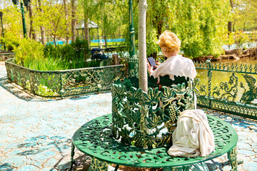 Mature beautiful woman traveler, sitting on the bench of the park and using mobile phone. Active...