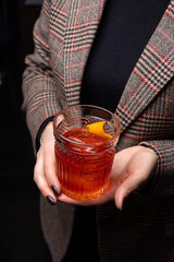 Cocktail negroni in the hands of a young woman.