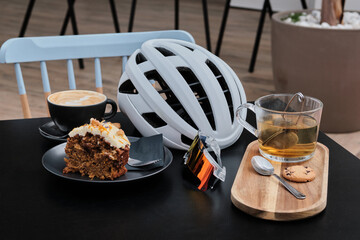 Coffee cycling ride. Cyclist enjoying coffee in the cafe after riding. Cup coffee and cycling helmet with sunglasses on the table.