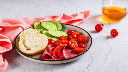 Girl dinner of smoked sausage, cucumbers, cherry tomatoes and buns on a plate web banner