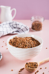 Raw buckwheat in a bowl and wooden spoon on the table vertical view