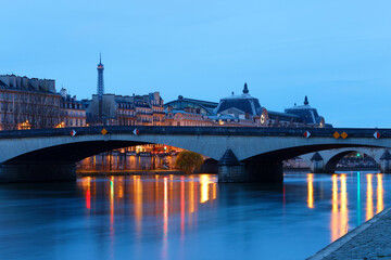 Night view of the banks of the Seine in Paris, France, with Carrousel bridge , Ouai Voltaire and beautiful sky and reflections