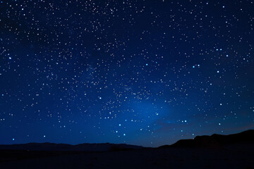 A dark sky with many stars and a mountain in the background