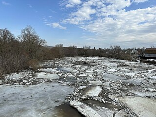 flood on the river in spring. ice floes float on the river against the background of a blue sky...