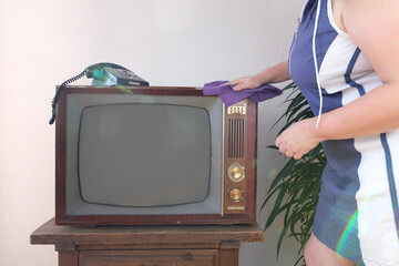 woman wiping down old television set, taking care household chores and cleaning vintage...