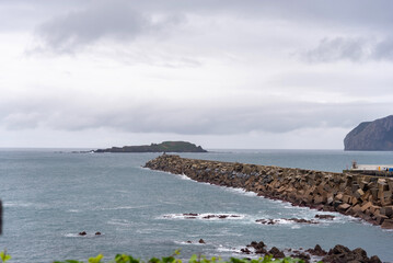Panoramic view of the landscape of the Basque coast with its mountains and cliffs in the background from the tourist town of Bermeo with the sea calm and the sky cloudy.