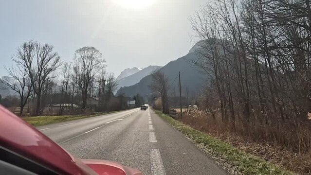 Driving along the road with bike path, shot from the red car moving in the French Alps close to Grenoble in winter