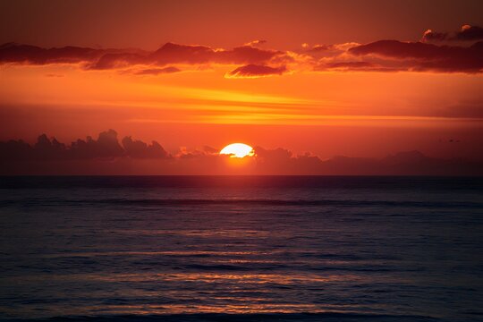 Golden hues illuminate the horizon as dawn breaks over ocean