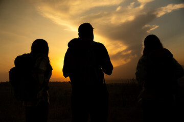 Silhouette of three mexican friends looking to the popocatepetl volcano at sunset