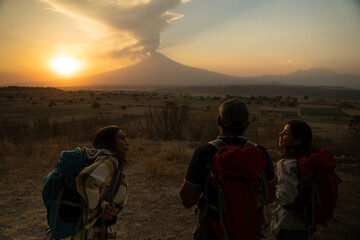 Group of three mexican hiker friends that watches the Popocatepetl at sunset in San Jeronimo Tecuanipan, Puebla, Mexico