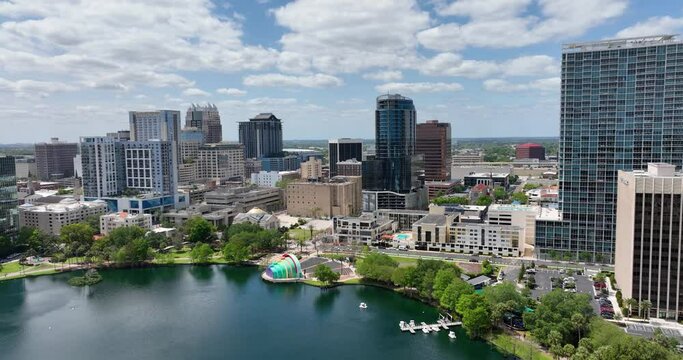  Downtown Orlando skyline overlooking the tranquil Lake Eola Park with its iconic fountain and urban backdrop.