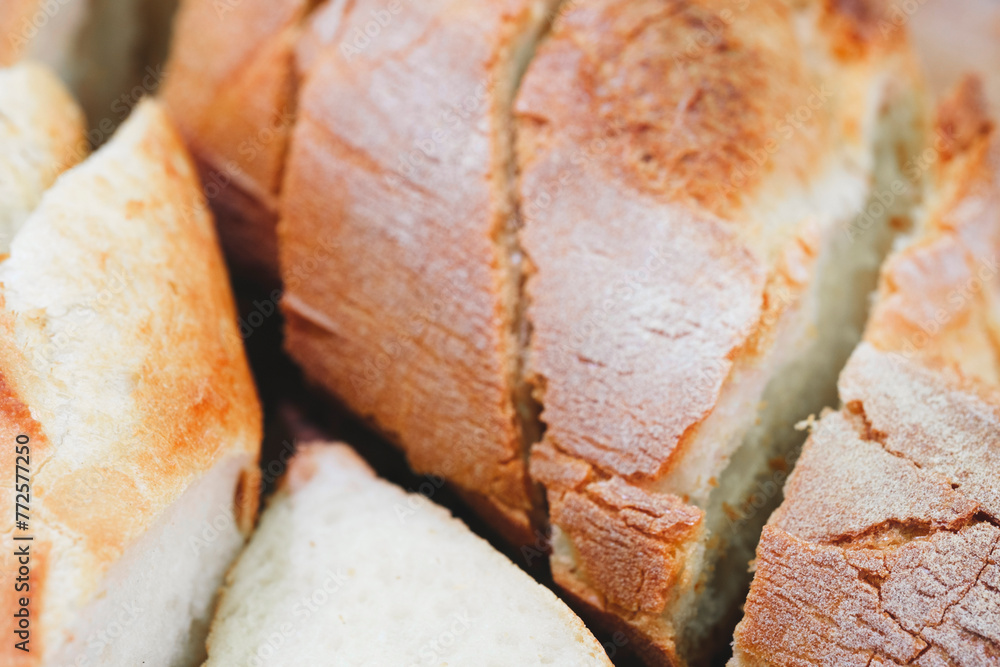 Poster A close up of a loaf of bread with a few slices missing. The bread is white and has a slightly brown crust. The slices are cut in half, revealing the soft, fluffy interior