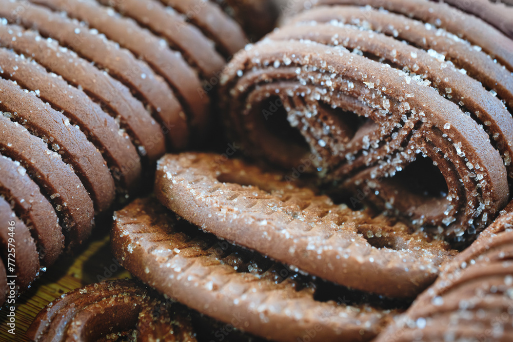 Poster A close up of a bunch of chocolate cookies with sugar sprinkled on top. The cookies are stacked on top of each other, creating a visually appealing and delicious display. Concept of warmth and comfort