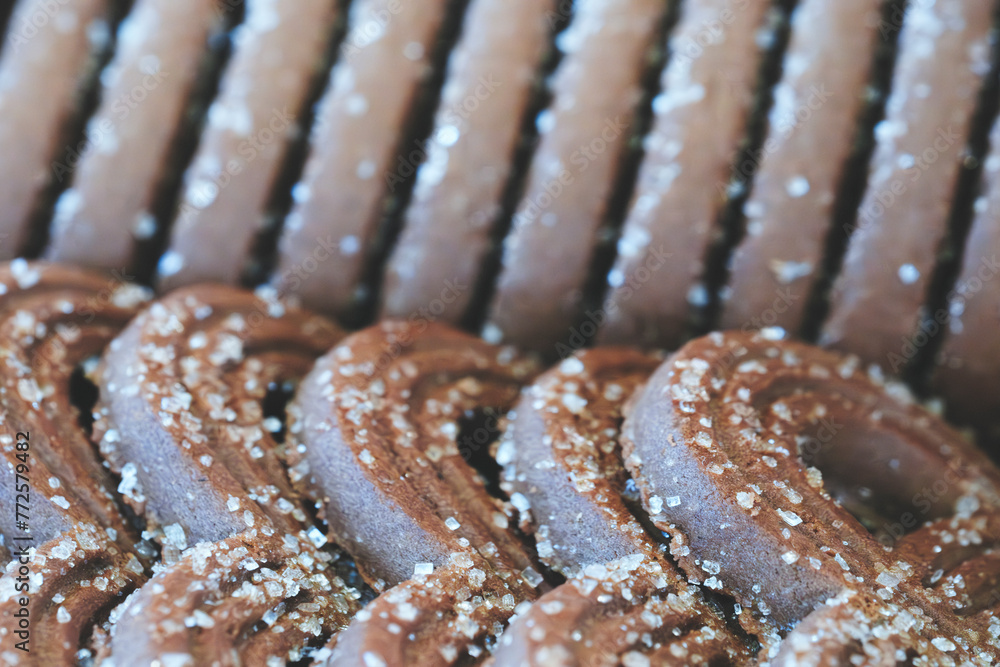 Poster A close up of a bunch of chocolate cookies with sugar sprinkled on top. The cookies are stacked on top of each other, creating a visually appealing and delicious display. Concept of warmth and comfort