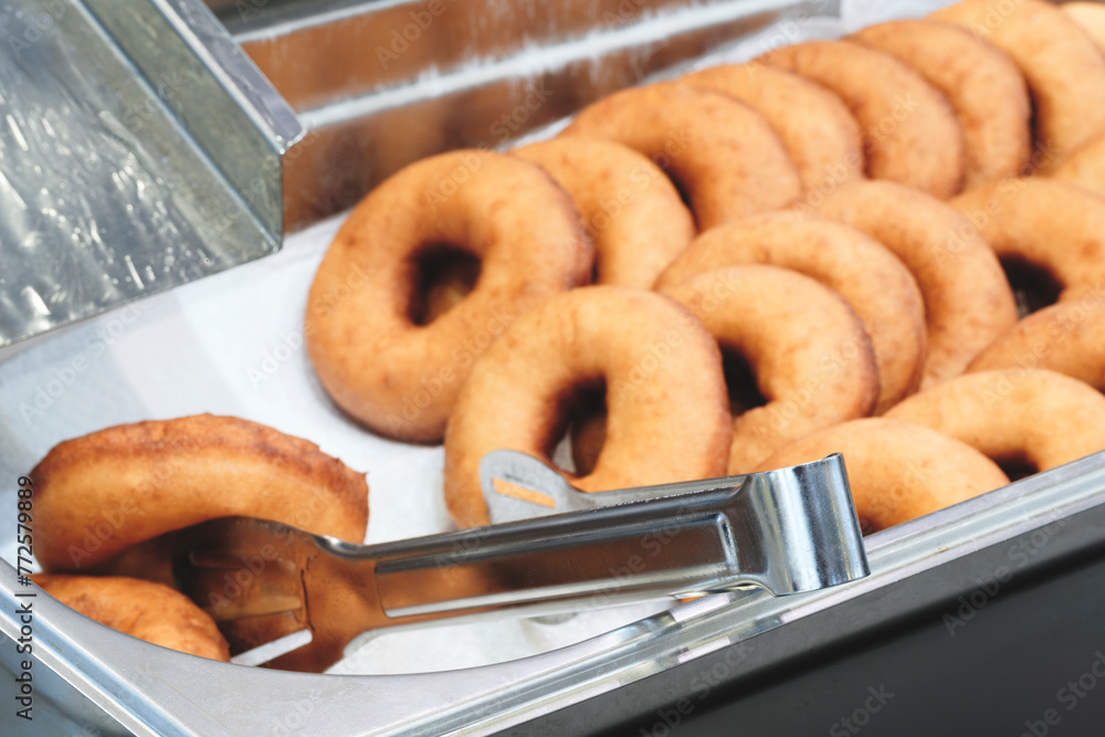 Poster A stack of donuts with a brown glaze. The donuts are piled on top of each other, creating a visually appealing and appetizing display