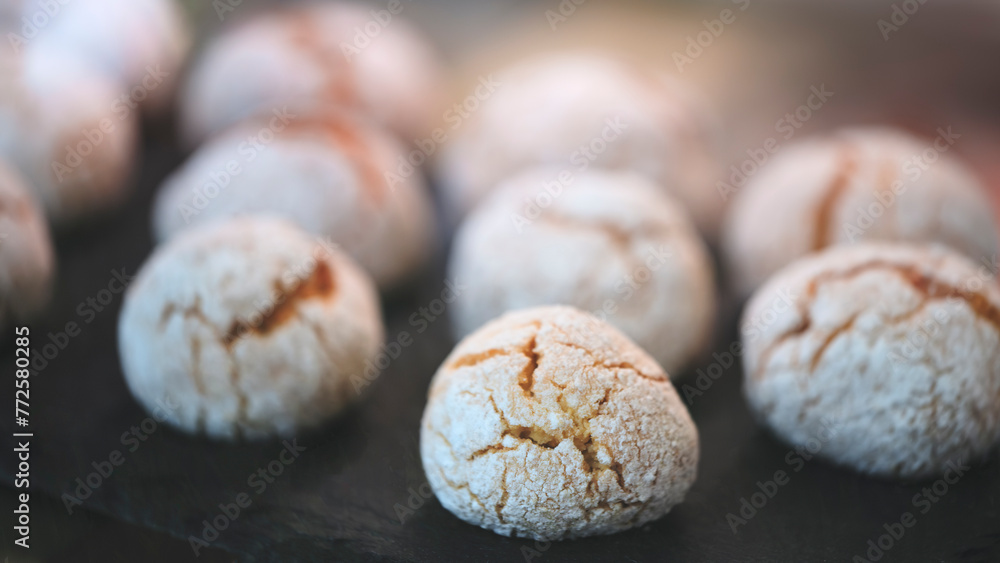 Poster A close up of a plate of cookies with a black background. The cookies are small and white, and they are arranged in a neat row. Concept of simplicity and elegance