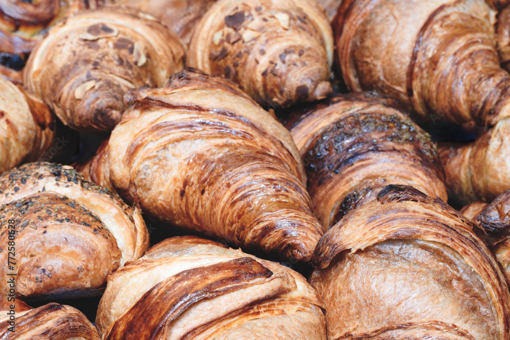 Poster a stack of croissants with nuts and chocolate chips. the croissants are brown and have a crispy text