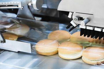 Conveyor belt next to a hamburger bun. All buns are divided into halves of the same size and shape and are packed in packaging film for sale or transportation.