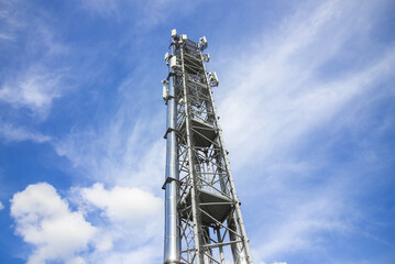 A tall tower with a lot of antennas on top. The sky is blue with some clouds