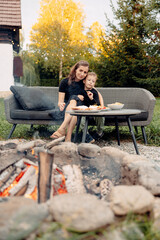 A joyful mother and son share a moment of delight on the outdoor patio, gathering around the fire...