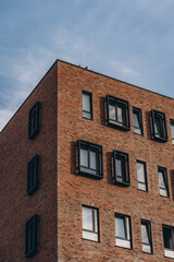 Fototapeta na wymiar Brick brown modern building with black rectangular decorative frame on windows, corner of house