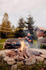 Garden Fire Pit Amidst Blurred Background of a Man Lounging on the Outdoor Sofa