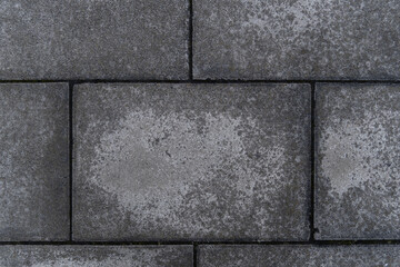 A close-up of a row of gray, rectangular bricks. Bricks appear to be old and weathered, with some cracks and chips on the surface