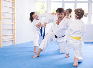 Judo or jiu-jitsu classes - family with two children practicing grabbing and throwing on sports mats