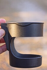hand holding one empty black plastic cup holder on the street on a gray background
