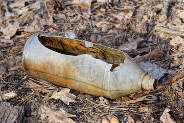 one white plastic broken bottle lies on the gray ground on the street