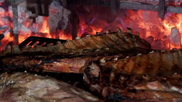 slow motion video of pork ribs cooking slowly on a restaurant charcoal grill