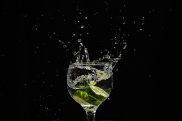 A band of lemon falling into a wine glass with water. Splash effect.