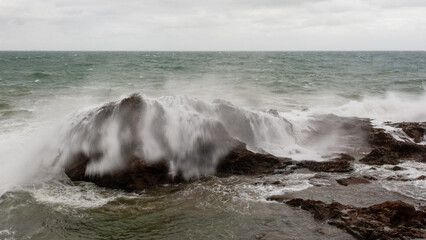 Sea waves crashing hard against a rock in winter.