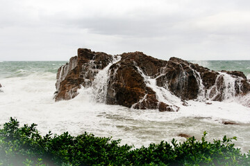 Obraz premium Immense sea rock covered by a large wave. Force of nature.