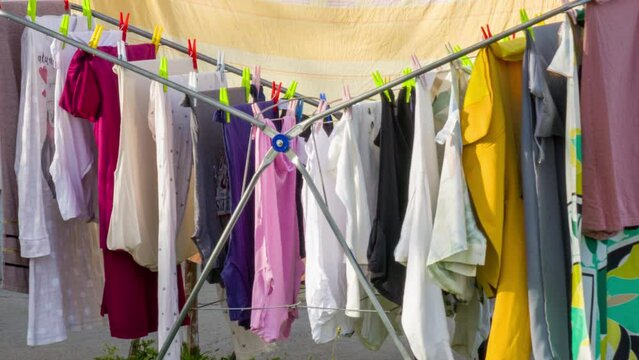 Clothes drying rack on sunny and windy day - colorful laundry hanging.