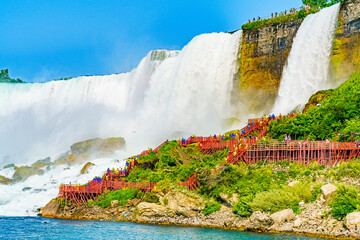 Throngs of visitors on red walkways at Cave of the Winds, with the powerful Niagara Falls in the background, showcasing the raw beauty of this natural wonder. Goat Island, Niagara Falls, New York, USA