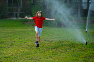 Fototapeta na wymiar Child play near automatic sprayers in the garden. Watering in the garden. Kid freshness of nature. Automatic lawn sprinkler watering grass. Garden irrigation system watering lawn. Sprinkler system.
