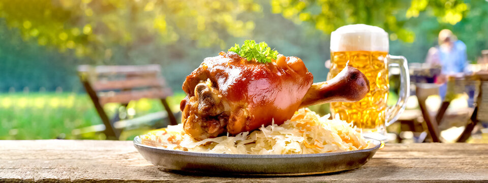 Schweinshaxe mit Sauerkraut und Bier im Biergarten 