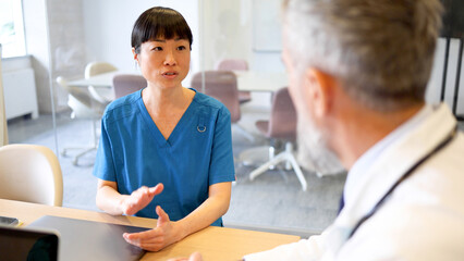 Japanese nurse and an older doctor having a meeting at the hospital office