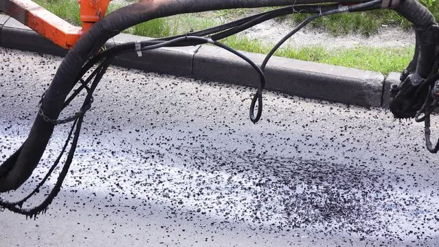 Road worker sprays hot bitumen to cover holes or cracks in the asphalt road.